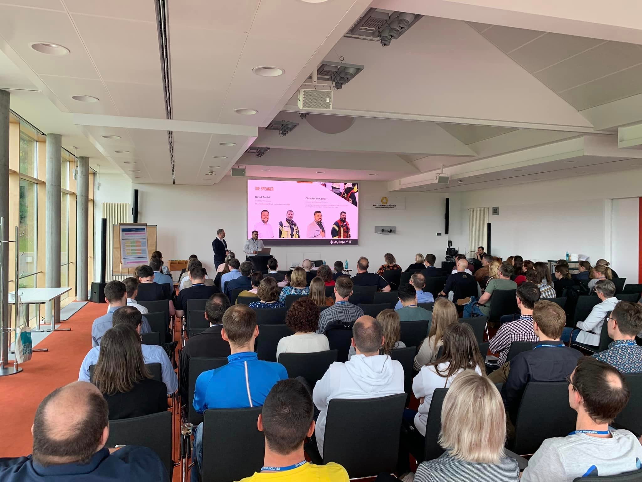 Audience at a speaking session with Mahoney IT on screen